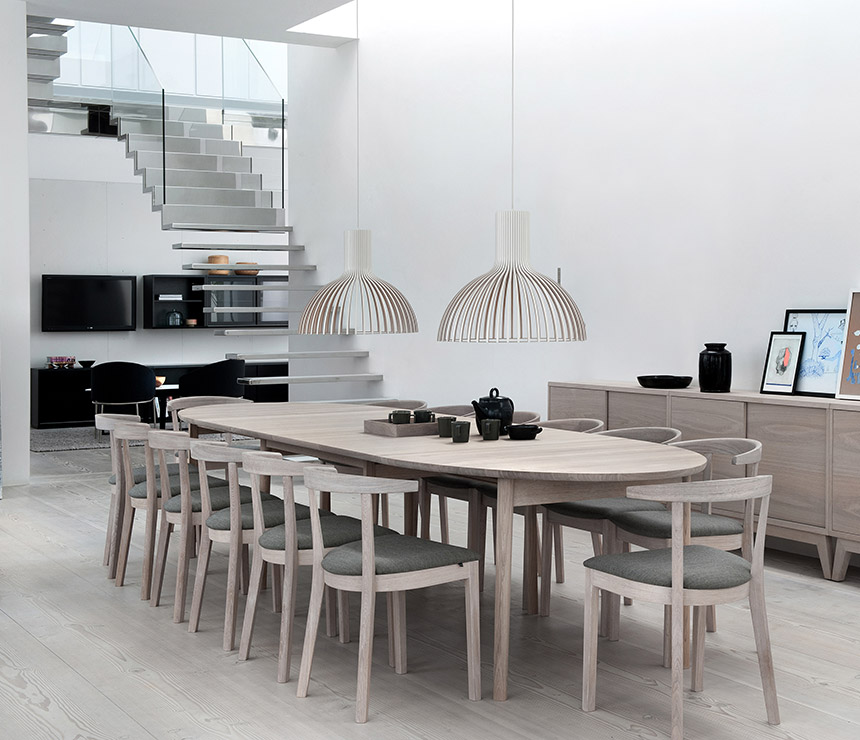 Elliptical oak dining table shown extended to seat 14