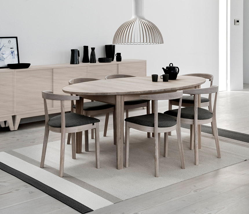 Light wood ellipse-shaped dining table that seats 6 to 14
