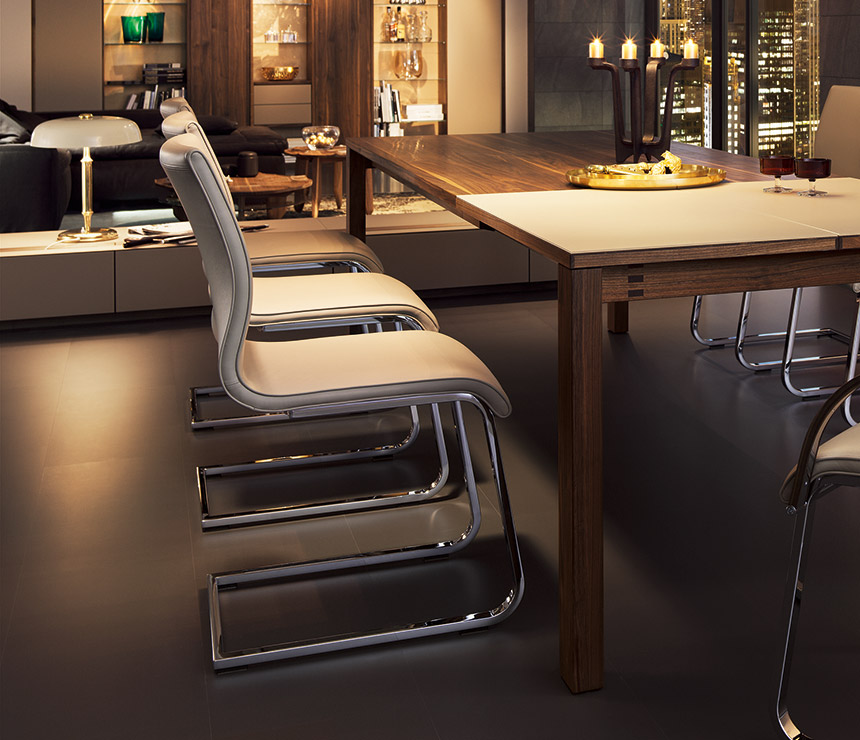 Luxury white leather upholstered Magnum cantilever dining chair shown with a Magnum table